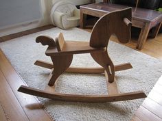 a wooden rocking horse sitting on top of a white rug