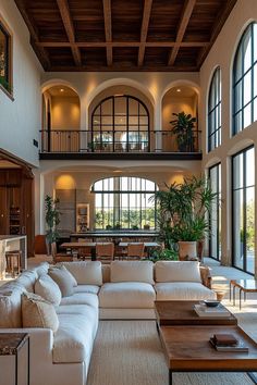 a large living room with high ceilings and lots of windows on the wall, along with white couches