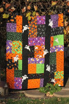 a halloween quilt hanging on the side of a fence with pumpkins and ghostes