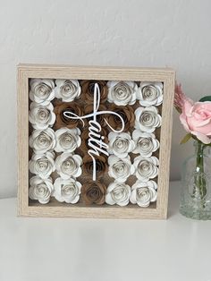 a wooden frame with paper flowers and the word love spelled in cursive writing