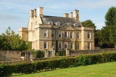 a large building with many windows on the front and side of it, surrounded by greenery