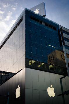 an apple store is shown in front of a building with the sky reflecting off it's windows