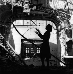 a woman standing in an old building with her hands up to the ceiling and looking at something