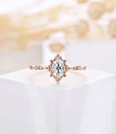 an engagement ring on top of a white box with gold trimmings and diamonds