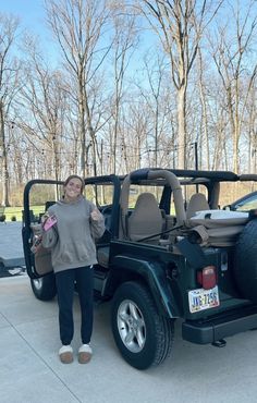 a woman standing next to a black jeep