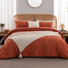 a bed with an orange comforter and pillows