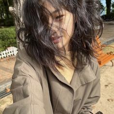 a woman with long hair sitting on a bench