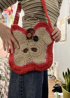 a woman is holding a crocheted purse with a monkey face on the front