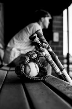 a baseball glove and ball sitting on top of a wooden bench next to a man