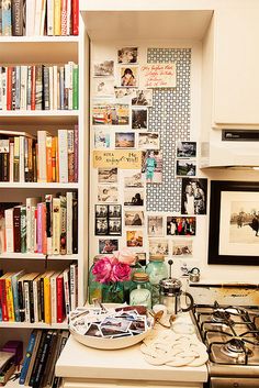 a kitchen with bookshelves full of books and pictures on the wall behind the stove