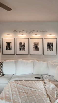 a living room with white couches and pictures on the wall above them in black and white