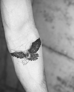 a black and white photo of a bird tattoo on the left inner arm, which has a circle around it