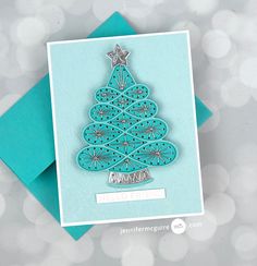 a card with a christmas tree cut out of it's side on top of a blue envelope