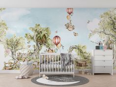 a baby's room with a mural and crib in the foreground, there is a dresser next to it