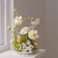 a white vase filled with lots of flowers on top of a window sill