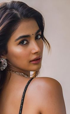 a beautiful young woman in a black dress posing for the camera with her hair pulled back