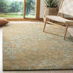 a living room area with a chair, window and rug on the floor in front of it