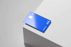 a blue credit card sitting on top of a white table next to a gray wall