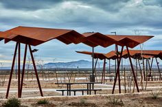 several metal structures in the desert with mountains in the background