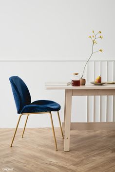 a blue chair sitting in front of a table with a vase on top of it