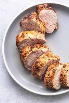 sliced pork on a plate with seasoning sprinkled around the top and sides