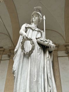 a statue of a woman holding a basket and a cane in her hand, with an arched ceiling above it