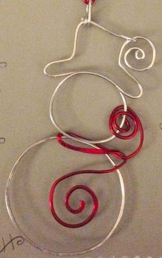 a wire wrapped necklace with red beads and silver wires hanging from it's sides