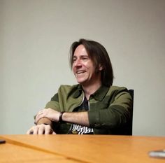 a man sitting at a table smiling for the camera