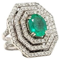 Ring size: 7 This incredible, jaw-dropping emerald and diamond cocktail ring is the absolute epitome of glamour. It features a single oval cut natural emerald in a stunning bluish-green color, double prong set at the center of the piece. A triple halo of icy white diamonds surround the center stone in a bold, octagonal shape, filling the finger from end to end with unbelievable sparkle. The white gold setting also really enhances the white brilliance of the diamonds. Set on a dome plate beneath the ring are additional pave diamonds, as well as along the top portion of the split shank, allowing the shimmering stones to be present from every angle. This is certainly a 'WOW' ring that will not go unnoticed! Ring size: 7 Weight: 22.4 grams Metal: 14 Karat White Gold Natural Diamonds: 5.81 ctw Luxury Fine Jewelry Green Halo Ring, Dazzling Oval Emerald Ring In Platinum, Platinum Oval Emerald Ring With 17 Jewels, Oval Platinum Emerald Ring With 17 Jewels, Diamond Cocktail Ring, White Gold Set, Diamond Jewelry Designs, Diamond Cocktail Rings, Bluish Green