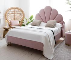 a bedroom with a pink bed and wicker chair in front of the window,