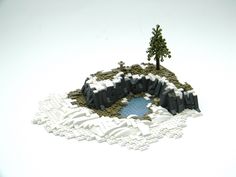 a small pond surrounded by snow and rocks with trees in the background on a white surface