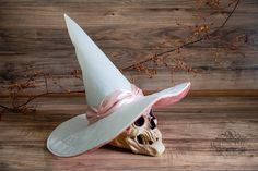 a skull wearing a white hat with a pink ribbon on it's head sitting on a wooden floor