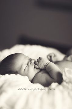 a black and white photo of a baby laying on it's back