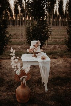 a table with flowers and a cake on it in the middle of an open field