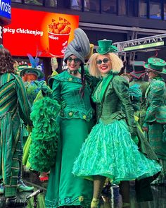 two women dressed in green standing next to each other at a carnival or parade event