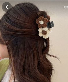 a woman with long brown hair wearing a flower clip