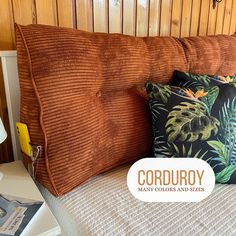 a close up of a pillow on a bed near a lamp and bookcase with the words corduroy many colors and sizes