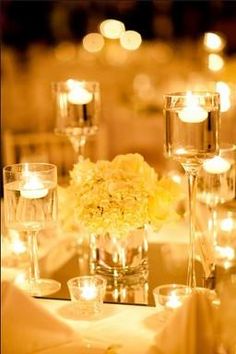 the centerpieces are filled with white flowers and lit candles at the head table