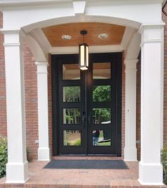 the front entrance to a home with double doors and brick walkway leading up to it