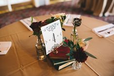 a table topped with books and vases filled with flowers sitting on top of a table