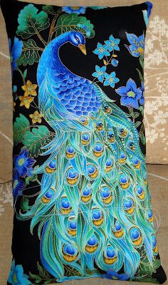 a blue peacock sitting on top of a black pillow