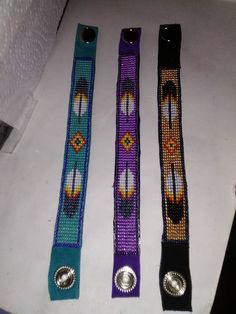 three beaded belts sitting on top of a white table next to each other,