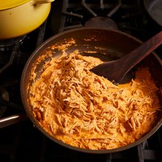 a pan filled with food sitting on top of a stove next to a wooden spoon