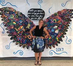 a woman standing in front of a wall with wings painted on it