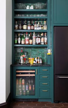 a kitchen with green cabinets and shelves filled with bottles, glasses, and other condiments