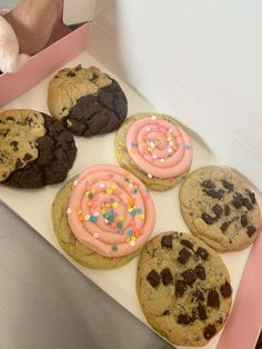 a box filled with chocolate chip cookies covered in frosting and sprinkles