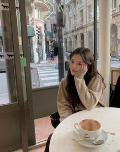 a woman sitting at a table with a cup of coffee