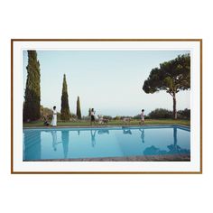 two people standing near a swimming pool with trees in the background and one person sitting on a bench