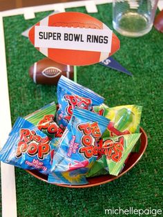 a bowl filled with gummy footballs on top of a green field