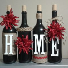 three wine bottles decorated with red poinsettis and the word home on them